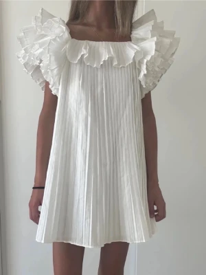 Vit plisserad kortklänning med volang - Superfin klänning, perfekt till student eller skolavslutning! Lånad bild!💕