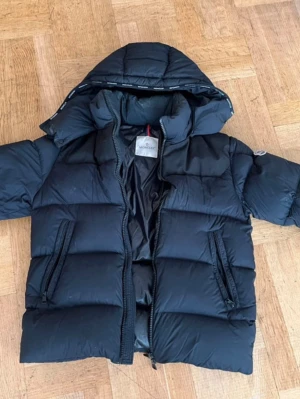 Moncler jacka - Mycket bra skick dock ett litet hål på armen som är igensytt. Luvan går att ta av
