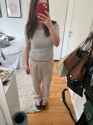Beiga linnebyxor med resårmidja - Säljer ett par beiga linnebyxor med avslappnad passform och resår i midjan. Byxorna är raka i modellen och har en naturlig, ljusbeige färg som passar till det mesta. Perfekta för en chill och stilren look. Materialet är linne vilket gör dem svala och sköna. Endast använda fåtal gånger 😽😽