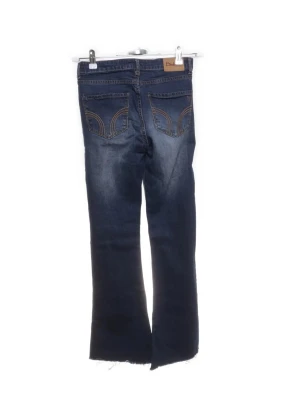 Mör​kblå bootcut jeans från Diesel - Säljer ett par mörkblå bootcut jeans från Diesel med slitna detaljer och råa, avklippta benslut. Jeansen har klassiska fem fickor och snygga kontrastsömmar på bakfickorna. Perfekta för en avslappnad och trendig look.
