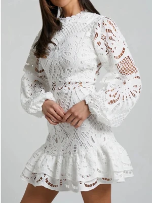 Vit spetsklänning med volang - Superfin vit kort klänning i spets med volangkant och långa puffärmar. Klänningen har hög hals och vackra broderade detaljer som ger en romantisk vibe. Perfekt för dig som vill sticka ut med en elegant och trendig look. Endast provad 