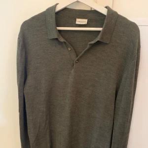 Grön merinoullströja från John Henric - Grön långärmad pikétröja från John Henric i 100% merinoull. Klassisk krage och knäppning med två knappar framtill. 