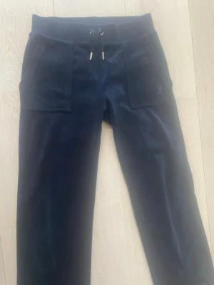 Mörkblått  juicy couture sett - Säljer ett mörkblått sett från Juicy Couture. Setet består av en zip-hoodie med fickor och dragsko samt matchande byxor med resårmidja och fickor fram.tröjan är i storlek M och byxorna i Xs. 