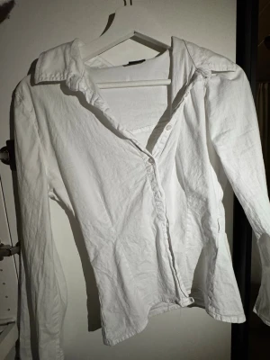 Vit skjorta från Gina Tricot figursydd - Klassisk vit skjorta från Gina Tricot i storlek 36. Skjortan har lång ärm, krage och knappar framtill. Perfekt basplagg med enkel och clean look, tillverkad i mjukt bomullsmaterial.