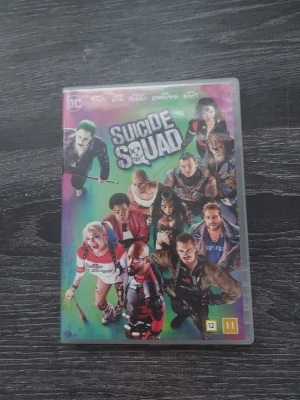 Suicide Squad DVD - Säljer en färgstark DVD-utgåva av filmen Suicide Squad från DC. Omslaget har en mix av neonfärger och visar flera ikoniska karaktärer från filmen. Plastfodralet är standardformat och har tydliga tryck med titeln och logotyper. Perfekt för filmälskare och samlare.