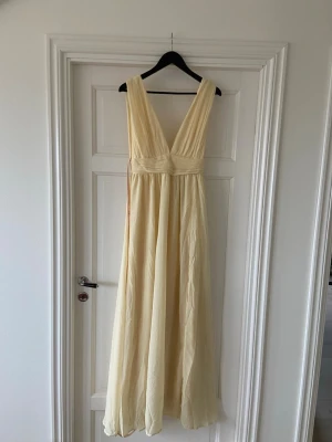 Ljusgul långklänning med v-ringning - Ljusgul balklänning/sommarklänning från lulus. V ringad och slits på en sidan. Helt ny med prislapp och plombering.