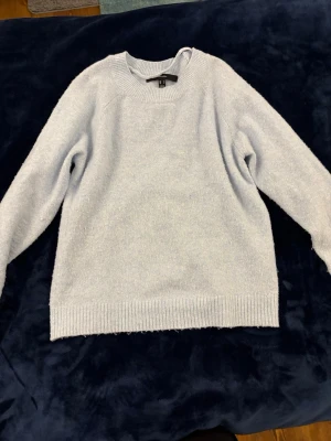 Ljusblå stickad tröja Vero Moda - Mysig ljusblå stickad tröja från Vero Moda med rund halsringning och ribbade muddar vid ärmslut och nederkant. Tröjan har en enkel och avslappnad passform, perfekt för kalla dagar. Materialet känns mjukt och behagligt mot huden.