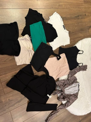 Mix av toppar i olika färger och stilar - Säljer ett paket med flera toppar i olika färger och modeller, bland annat svarta, vita, gröna och beige linnen samt en leopardmönstrad omlottopp. Flera är croppade och ärmlösa, vissa med smala axelband. Perfekt för dig som vill variera din stil!