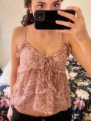 Rosa mönstrad volang linnetopp - Säljer en jättegullig rosa linnetopp med volanger och snörning framtill. Toppen har tunna axelband och ett gulligt unikt mönster. Använd fåtal gånger och i perfekt skick!💕