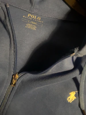 Blå hoodie från Polo Ralph Lauren - Snygg blå hoodie från Polo Ralph Lauren med dragkedja framtill, storlek S. kom privat för mer information! 