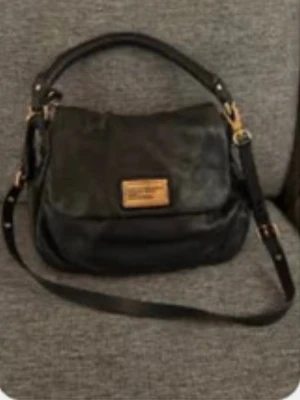 Svart Marc by Marc Jacobs handväska - Snygg svart handväska från Marc by Marc Jacobs i äkta skinn. justerbar axelrem och ett stort lock med logoplatta. Insidan är fodrad med beige och svart textmönster med märkets bokstäver. Nypis är 5000kr!!!