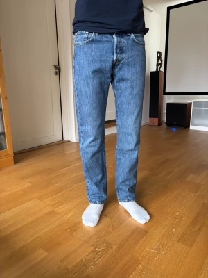 Blå raka jeans från Levi's - Klassiska blå jeans från Levi's i rak modell med fem fickor och normal midja. Jeansen har den ikoniska röda Levi's-lappen på bakfickan och ett brunt lädermärke i linningen. Jeansen är i bra men använt skick. Storlek W28 L30