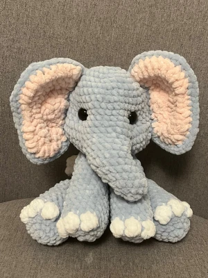 Blå virkad elefant gosedjur - Supermjuk och fluffig virkad elefant i ljusblått garn med stora öron i ljusrosa och vita detaljer på tassarna. Svarta plastögon ger ett gulligt uttryck. Perfekt som present eller dekoration i sovrummet.