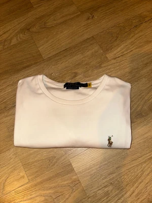 Vit t-shirt från Polo Ralph Lauren - Klassisk vit t-shirt från Polo Ralph Lauren med rund halsringning och den ikoniska broderade loggan på bröstet. Tillverkad i mjuk bomull för en skön känsla och stilren look.