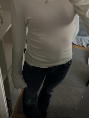 Vit ribbad tröja - Säljer en stilren vit ribbad tröja från Etirel. Tröjan har en rund halsringning och långa ärmar, perfekt för en enkel och snygg look. Passar bra till både jeans och kjol. Perfekt basplagg i garderoben!