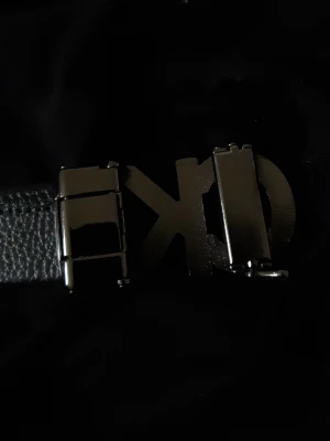 Svart skärp från Calvin Klein - Snyggt svart skärp från Calvin Klein med ett stilrent CK-spänne i silverfärgad metall. Bältet är gjort i präglat skinn och passar perfekt till jeans eller kostymbyxor. En klassisk accessoar som lyfter din outfit.