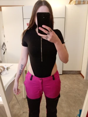 Svart body med dragkedja - Säljer en svart body med korta ärmar och en snygg dragkedja framtill. Bodyn har höga utskärningar på sidorna och är tight i passformen. Perfekt för dig som vill ha en stilren och edgy look. Materialet känns som syntet och polyester.