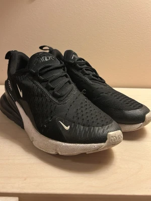 Nike Air Max 270 svarta sneakers - Svarta Nike Air Max 270 sneakers med vit sula och loggor på sidan.  Ovandelen är i mesh och textil sulan har en synlig Air Max-enhet. Använda.  Tyget har defekter se bilder. 
