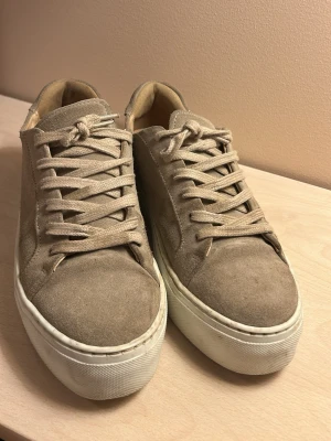 Beige mockasneakers med tjock sula, Rizzo - Stilrena sneakers från Rizzo i beige mocka med matchande skosnören och vit, chunky gummisula. Klassisk låg modell med rund tå. 