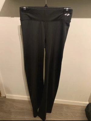 Svarta bootcut leggings - Säljer ett par svarta leggings med bootcut-ben och hög midja. De är tillverkade i ett stretchigt och mjukt material som sitter skönt på kroppen. Perfekta för dig som gillar en enkel och stilren look utan synliga loggor.