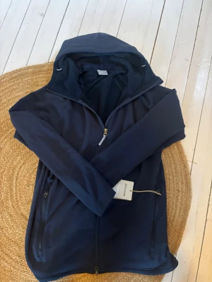 Mörkblå hoodie från HOUDINI - Svin snygg, fleece aktig hoodie som passar perfekt till en sen sommarkväll. Den är helt ny med lappen kvar. Köptes för 2300kr men säljer den för 1599. Hör av vid funderingar!