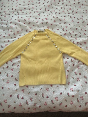  Populära gula ribbstickad tröja med knappar från Zara💛💛 - Snygg gul ribbstickad tröja med långa ärmar och dekorativa vita knappar längs axlarna. Tröjan har en rak passform och är tillverkad i ett mjukt, stretchigt material som känns skönt mot huden. Perfekt för dig som vill ha en färgklick i garderobe💛💛