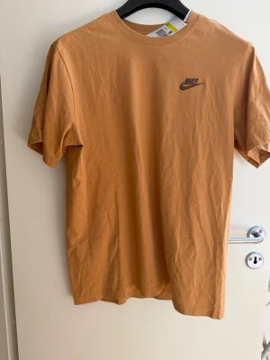 Nike T-shirt  - Helt ny och oanvänd Nike T-Shirt i ljusbrun färg med prislappen på i storlek S. Jag skulle säga att den är lite lite större än vanlig S.