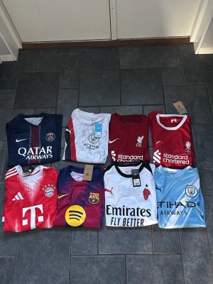 Fotbollströjor från toppklubbar - Säljer flera fotbollströjor från kända lag som PSG, Manchester City, Liverpool, Bayern München, Barcelona, AC Milan och Real Madrid. Tröjorna har tryck med spelarnamn som Haaland, Salah, Sané, Dembélé, Lamine Yamal och Leao. Färgerna varierar mellan röd, blå, vit och ljusblå. Perfekt för dig som älskar fotboll och vill bära ditt favoritlag.    Vill man köpa enskilda tröjor blir det:  275kr för Haaland, Lamine yamal och Dembele per tröja, 175kr för Liverpool tröjorna per tröja och 150 för Baryern