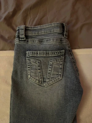 Grå tvättade jeans Gina Tricot - Säljer ett par blå tvättade jeans från Gina Tricot 14+ kollektionen med klassisk femficksmodell och snygga detaljer på bakfickan. Jeansen har normal midja, bälteshällor och är tillverkade i stretchigt denimtyg för skön passform. Med låg midja och utsvängda ben. Använd bara någon få gång.