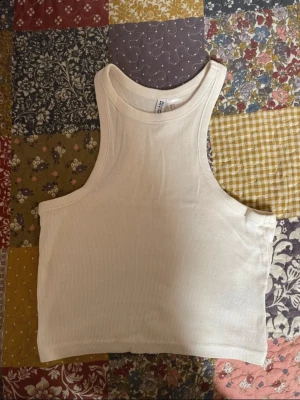 Krämvit ribbad croppad linnetopp H&M - Krämvit ribbad croppad linnetopp från H&M. Storlek S. Axelbredd: 18 cm. Längd: 40 cm.