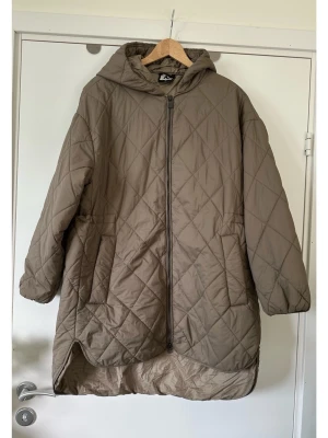 McKinley - brun /beige quiltad jacka med luva - storlek M / 38 - Stilren brun / ljusbrun quiltad jacka med huva och dragkedja framtill från outdoor-experten McKinley i storlek 38. Tidlös modell med praktiska fickor i sidorna och en dragsko på insidan i midjan för justerbar passform. Nederkanten har diskreta avrundade slitsar i sidorna för bra rörlighet. Klassisk kvalitetsjacka som kommer hålla säsong efter säsong. Mycket gott skick, som ny!