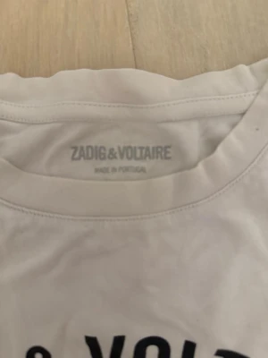 Vit Zadig & Voltaire t-shirt - Vit t-shirt från Zadig & Voltaire med svart tryck framtill. Den är inte i perfekt skick pågrund av några hål men ändå jätte fin! 