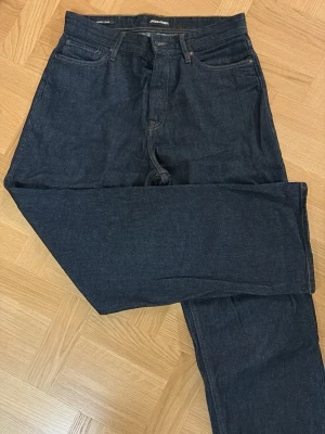 Mörkblå baggy jeans från Jack & Jones - Snygga mörkblå jeans från Jack & Jones med klassisk femficksmodell och raka ben. Jeansen har en stilren look med diskreta sömmar och patch med logga bak i midjan. Tillverkade i slitstark denim som passar perfekt till din vardagsstil.