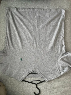 Grå v-ringad t-shirt från Ralph Lauren - Snygg grå t-shirt från Ralph Lauren med v-ringning och klassisk grön broderad logga på bröstet. Tillverkad i mjuk bomull och har korta ärmar. Perfekt basplagg för en clean och enkel stil.