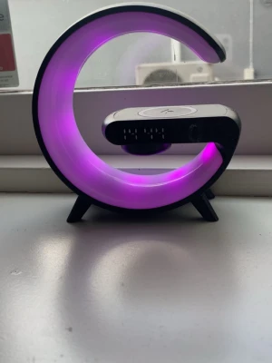 Månskensformad LED-lampa med laddare - Säljer en cool månskensformad LED-lampa med lila belysning och inbyggd trådlös laddare. Lampan har en modern design i svart och vitt plastmaterial och står stadigt på små ben. Perfekt som dekoration till skrivbordet eller gaminghörnan.