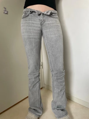Ljusgrå bootcut jeans st xxs  - Säljer ett par ljusgrå bootcut jeans med låg midja och klassisk femficksdesign. Jeansen har en snygg tvättad look och är tillverkade i mjukt denimtyg som ger en skön passform. Perfekta för dig som gillar en avslappnad men trendig stil.