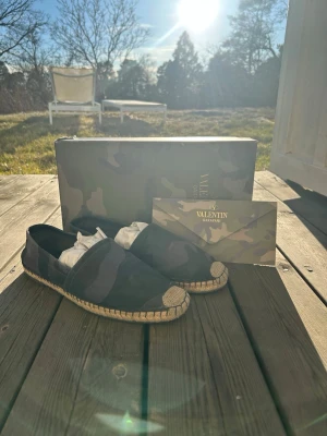 Valentino Espadrilles - Säljer dessa feta kamouflage Valentino Espadrilles! De är gröna, gråa och svarta. Strlk 42, 26cm inuti sulan. Passar perfekt till sommaren! Nypris 3695kr. Självklart äkta! Äkthetsbevis finns. Box och kuvert ingår! Hör av vid intresse!💯🍾