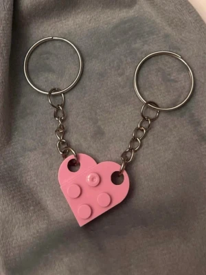 Nyckelring legobitar hjärta nyckelringar för par  - Ett gulligt par nyckelringar med var sin legobit som tillsammans bildar ett hjärta! Fint att dela med sin bästis, partner eller någon annan som betyder mycket. Varje legobit är ca 2 x 1,5 cm och hela nyckelringen är ca 6,5 cm lång.