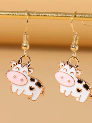 Söta örhängen med ko-motiv - Unika örhängen i form av gulliga kor med vit och rosa emalj samt svarta fläckar och små hjärtan. Krokarna är guldfärgade och örhängena har en lekfull och trendig design som sticker ut. Perfekta för dig som vill ha något annorlunda och roligt i smyckeskrinet.