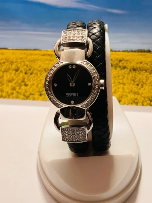 Esprit Damarmbandsur med svart flätat band - Snygg klocka från Esprit med svart urtavla och silverfärgade detaljer. Klockan har ett svart flätat band och glittrande stenar runt urtavlan samt på spännena. Perfekt accessoar för dig som gillar en elegant och modern stil.
