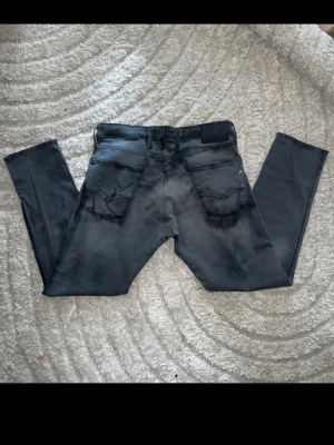 Replay Anbass jeans  - Gråa replay Anbass jeans med svart motiv på, liknande fade/fläckar. Jeanen är i mjukt jeans tyg med en slim passform. Midja 41cm, längd 94cm.  Jag har tyvärr ingen bild när jag bär jeansen på. För bättre inblick i passformen rekommenderar jag att googla på modellnamnet. För storleksguide kolla måtten noggrant då jeansen alltid kan vara uppsydda heller krympta och jag ej tar emot returer :) 1,95