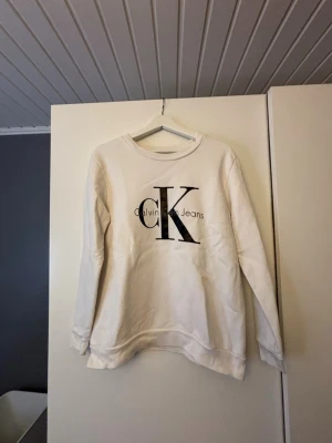 Vit sweatshirt från Calvin Klein Jeans - Snygg vit sweatshirt från Calvin Klein Jeans med stort CK-tryck på bröstet. 