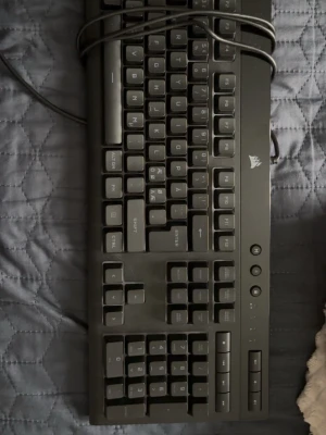Corsair svart mekaniskt tangentbord - Säljer ett svart mekaniskt tangentbord från Corsair med fullstora tangenter och numerisk del. Tangentbordet har en klassisk design med tydliga vita tecken på knapparna och ansluts via USB-kabel. Perfekt för gaming eller skrivarbete. Kan ändra färger på den! Använd 3 gånger maximalt!