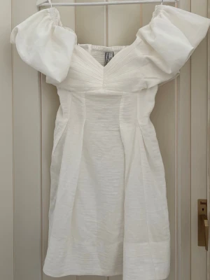 Vit kort klänning - Trendig vit kortklänning med  puffärmar. Perfekt till student eller bara att ha som sommar klänning. Klänning är off shoulder men går även att ha som ”vanligt” (se bild 3). Aldrig använd vara testad. Klänning är slutsåld och från forever new, köpt från asos. Nypris: 1350kr 