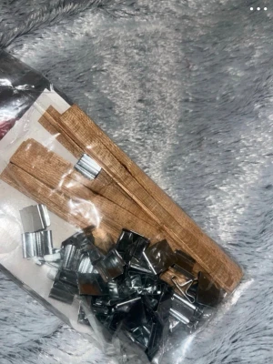 Paket med träpinnar och metallklämmor - Säljer ett paket med tunna träpinnar och små metallklämmor. Perfekt för pyssel, DIY-projekt eller modellbygge. Träpinnarna är ljusbruna och klämmorna är silverfärgade. Allt ligger i en genomskinlig plastpåse.