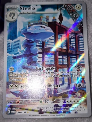 Steelix Pokémonkort holografiskt - Säljer ett holografiskt Steelix Pokémonkort med coolt motiv där Steelix står vid en byggarbetsplats. Kortet har skimrande effekt och visar attacker som Earthquake och Heavy Impact. Kortet är från serien Paradox Rift och har nummer 208/182.