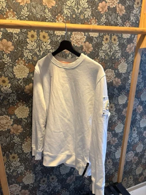 Moose Knuckles - Vit sweatshirt med rund hals och avslappnad passform. Den har ribbade muddar och en liten ficka med dragkedja på ärmen som ger en modern detalj. Perfekt för en enkel och stilren vardagslook. 