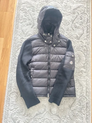 Moncler cardigan - Svart Moncler cardigan. Jackan är i bra skick och säljs eftersom den har blivit för kort för mig. Den är i storlek M, men passar även perfekt för någon som har storlek S. Luvan är avtagbar. Pris kan diskuteras!