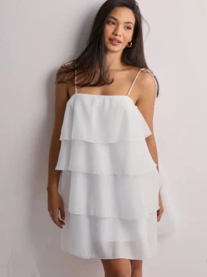 Vit volangklänning med tunna axelband - Säljer en superfin vit klänning med tunna axelband och flera lager volanger från gina tricot. Klänningen är kort och har en luftig, flowy känsla som passar perfekt till sommaren. Materialet känns lätt och svalt, och modellen ger en riktigt fräsch och trendig look.                                                                    Första bilden är lånad men resterande bilder är mina egna. Klänningen har några få defekter, små fläckar se bild. Men de syns inte. 