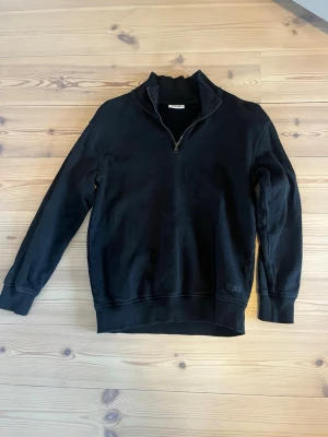 Svart halvzip topp från Kappahl - Svart långärmad topp från Kappahl med halv dragkedja och ribbad krage. Tillverkad i mjuk bomullsmix.